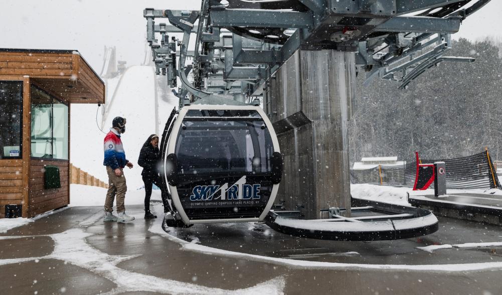 Two people hop on a gondola ride in the winter.