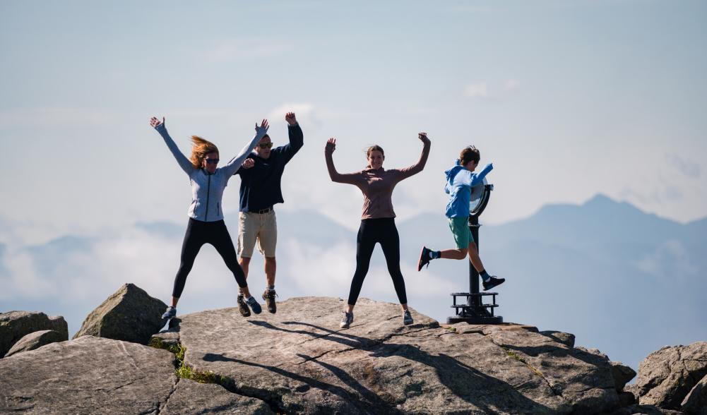 A family of four jumps on top of whiteface mountain.