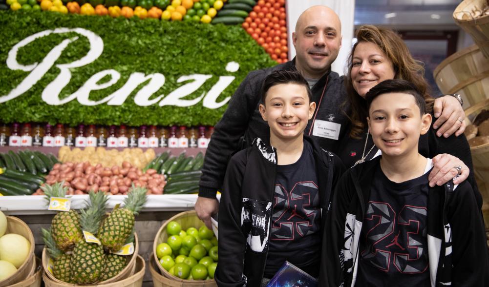 A family poses for a picture in front of a table at a conference.