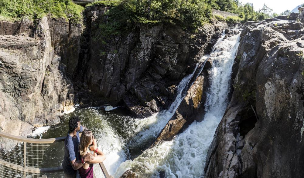 A couple looks off of a platform at a waterfall at High Falls Gorge.
