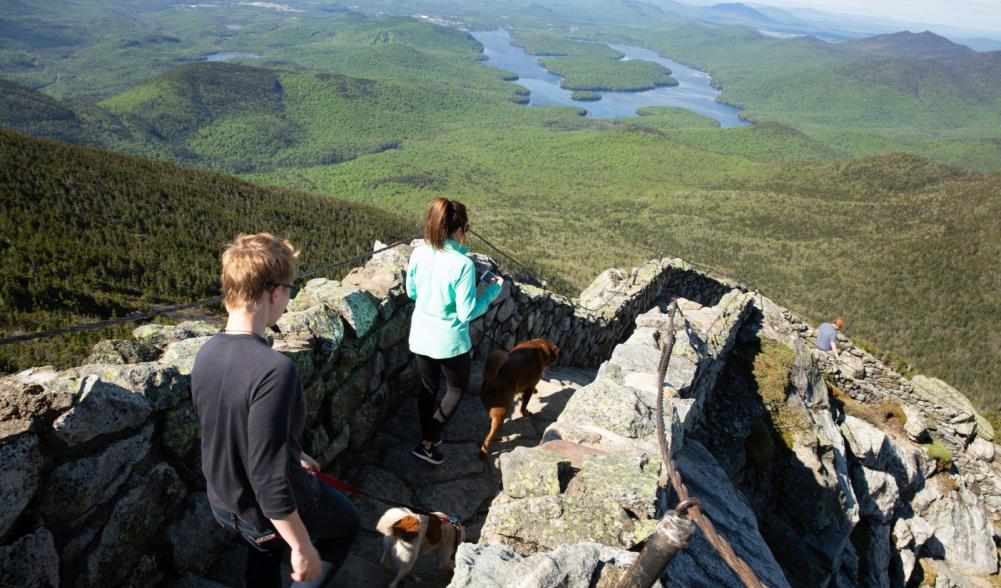 Two women walking down the stairs from the Whiteface Mountain weather station with mountains in the background.