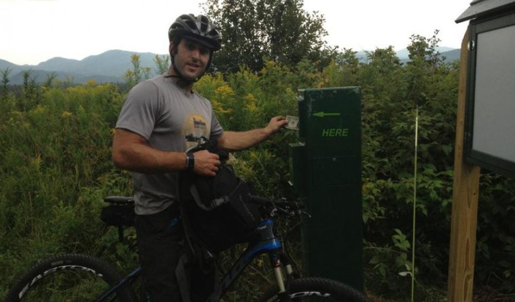 A rider making a donation in the box on the Lake Placid Club and Resort property