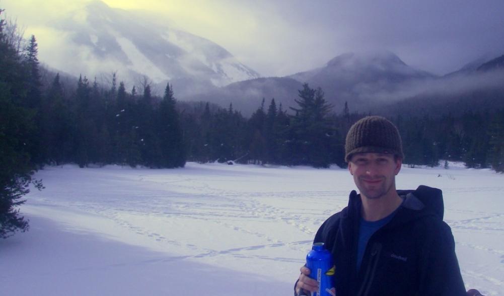 A skier takes a break at Marcy Dam (The terminus of the Whale's Tail Ski Trail)