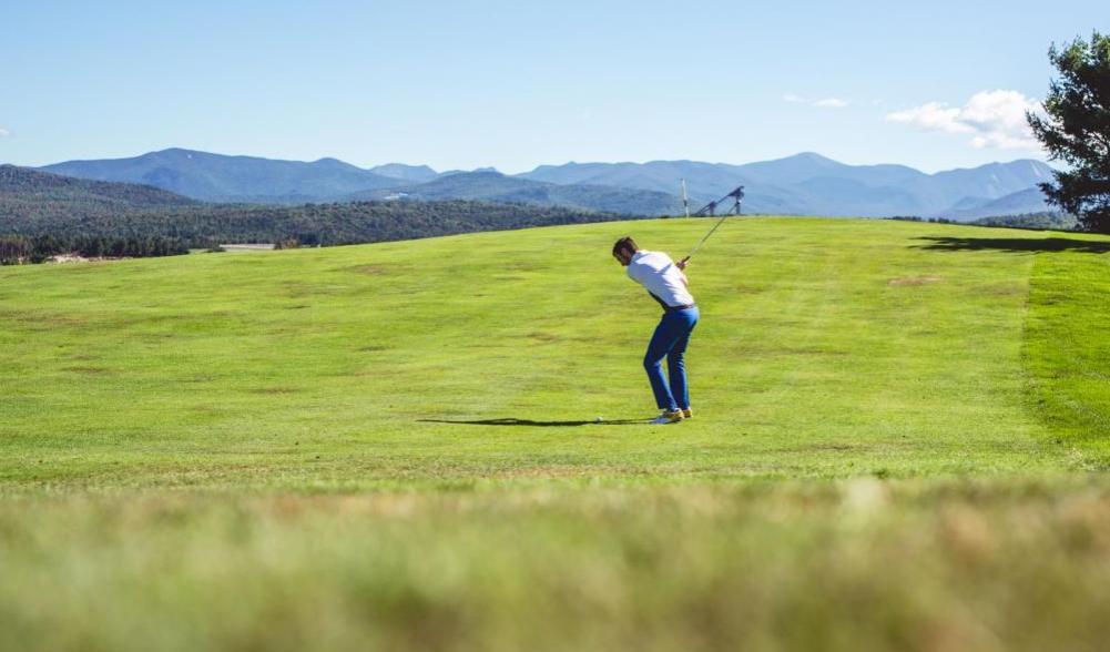 A male golfer swings on the fairway at a Lake Placid golf course.