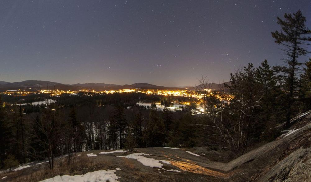 Night view of Lake Placid Village from Cobble Hill, with the High Peaks in the background on a starry-starry night