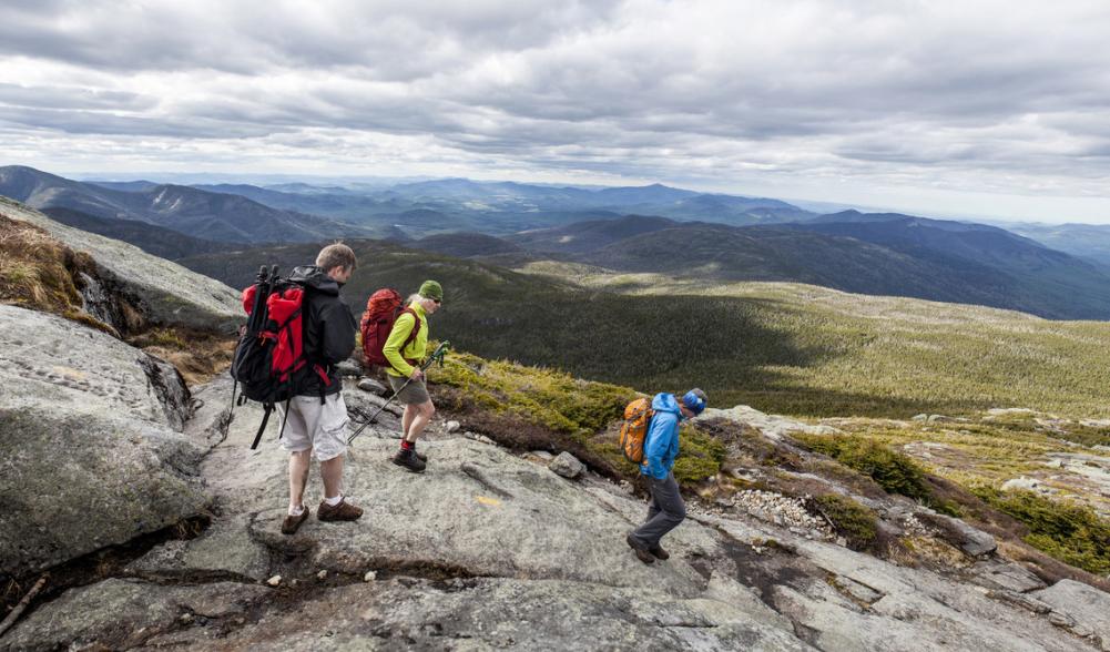 Three hikers descend Mount Marcy's north shoulder.