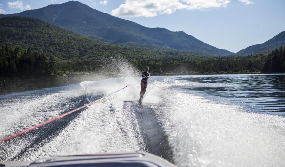A woman waterskis on Lake Placid with mountains in the background.