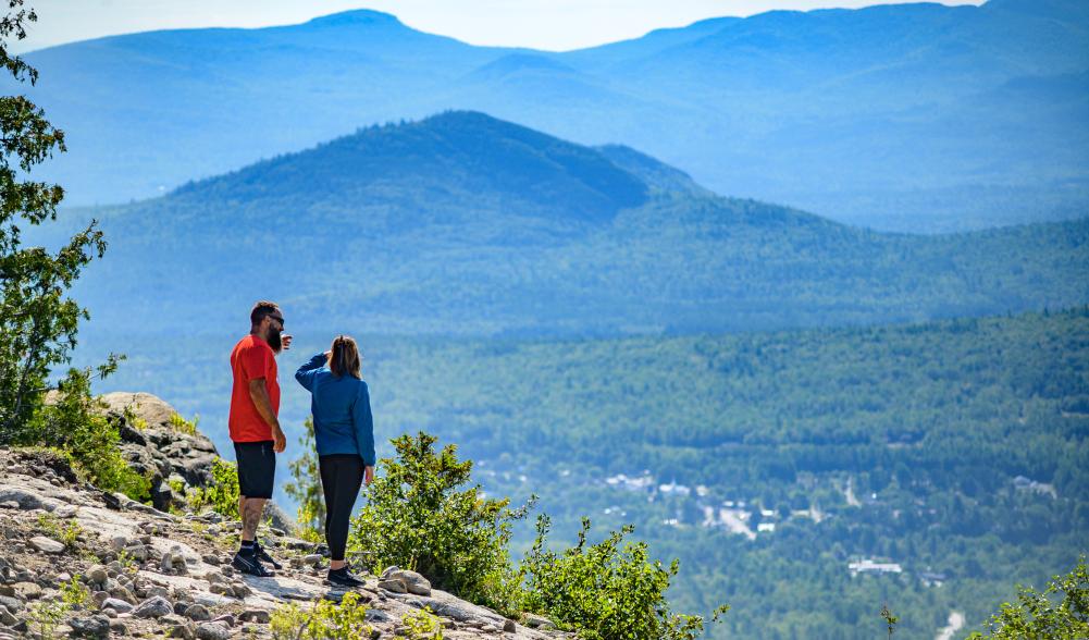A couple enjoying the view from Cobble Lookout, one of the more popular easy hikes near Lake Placid.