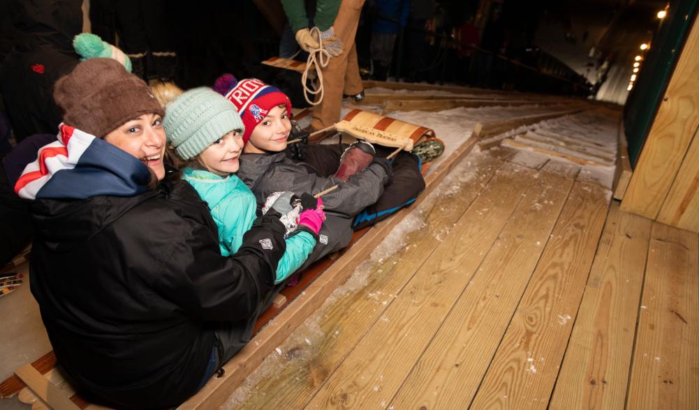 A woman and two children prepare to slide down the toboggan chute.