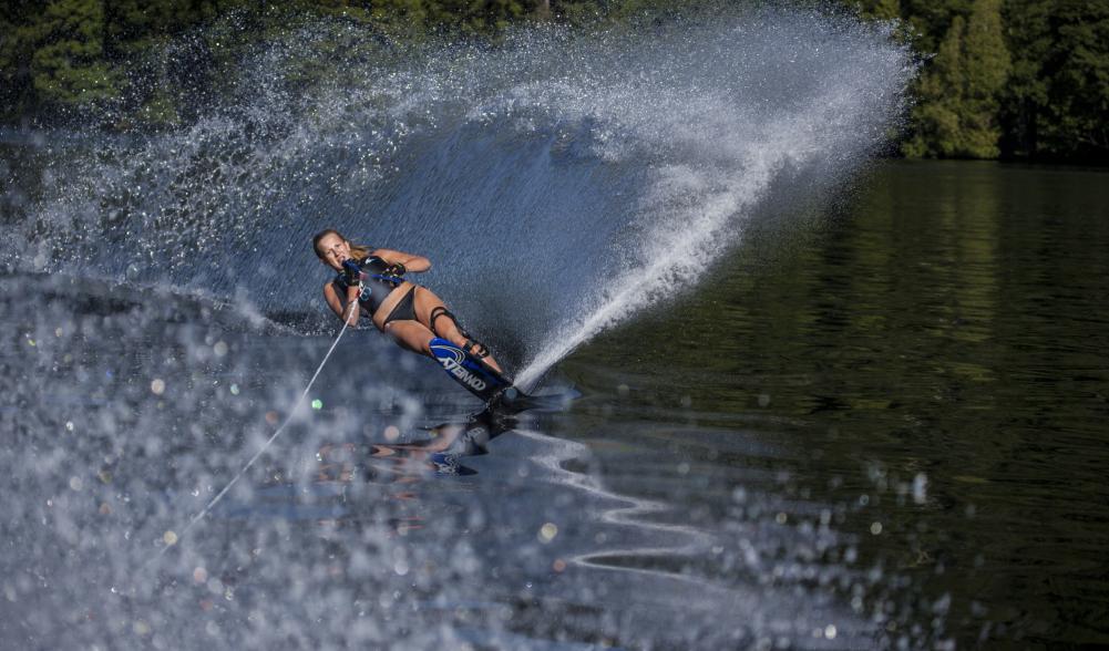A woman on water skis carves through Lake Placid lake.