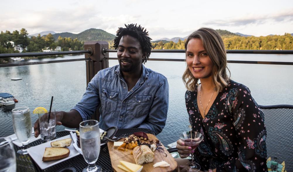 A couple enjoys a meal on the deck at Top of the Park with a lakeview.