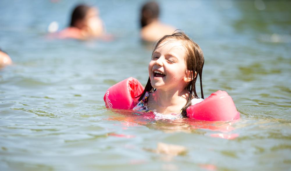 A girl in water wings laughs at the Mirror Lake Beach.