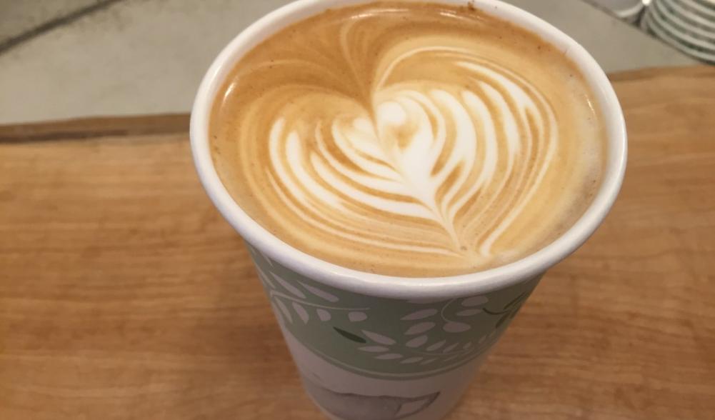 A latte in a paper cup on a table in one of Lake Placid's coffee shops