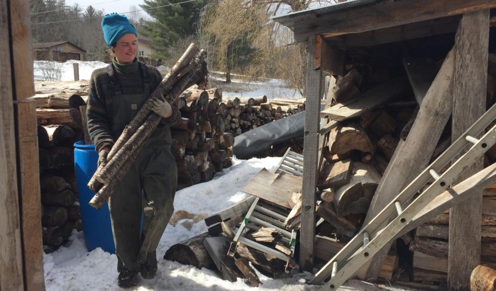 Lizzie, one of two assistants, is carrying wood for the wood fire stove beneath the evaporator.