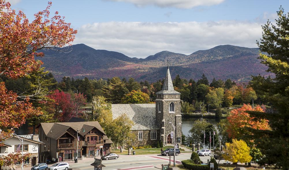 A scenic view of Mirror Lake and a local church amid fall foliage.