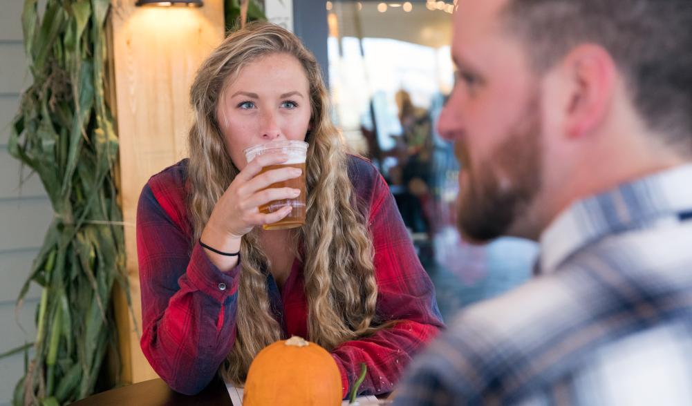 A young woman drinking a beer in Lake Placid in the fall.