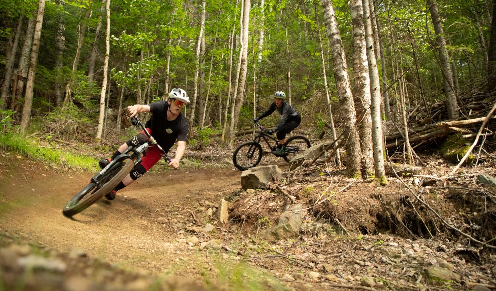 Two riders coming around a corner on one of Lake Placid's epic mountain bike trails