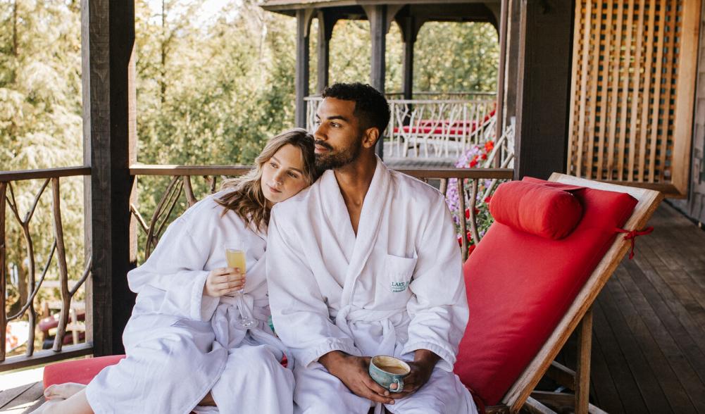 A man and woman sit in white robes at a resort.