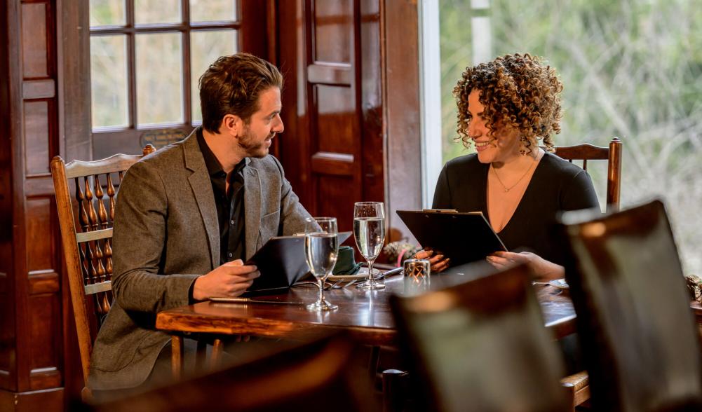 A man and woman look over menus in a lodge-style restaurant.