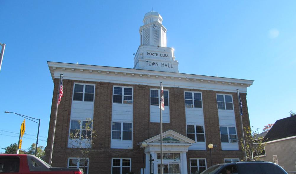 Looking up at the classic brick town hall with white bell tower.
