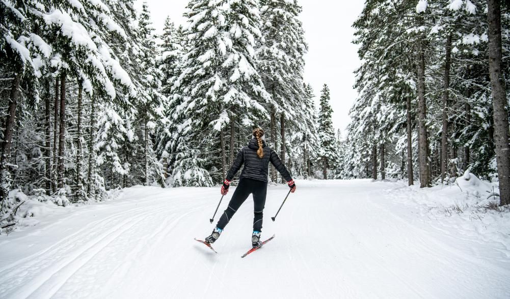 Woman cross-country skiing on snowy trail.