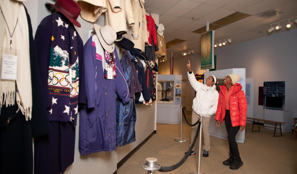 Two women admire historic uniforms at the Lake Placid Olympic Museum.