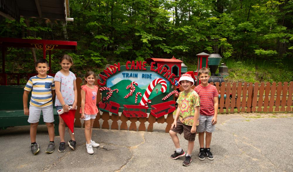 Five children standing in front of a Candy Cane Express Train Ride sign at Santa's Workshop.