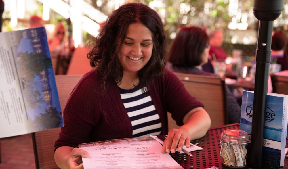 A woman studies the menu at The Cottage's outdoor dining area.