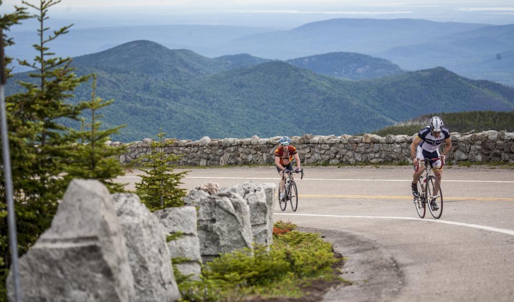 Two cyclists climb the Whiteface Toll Road.