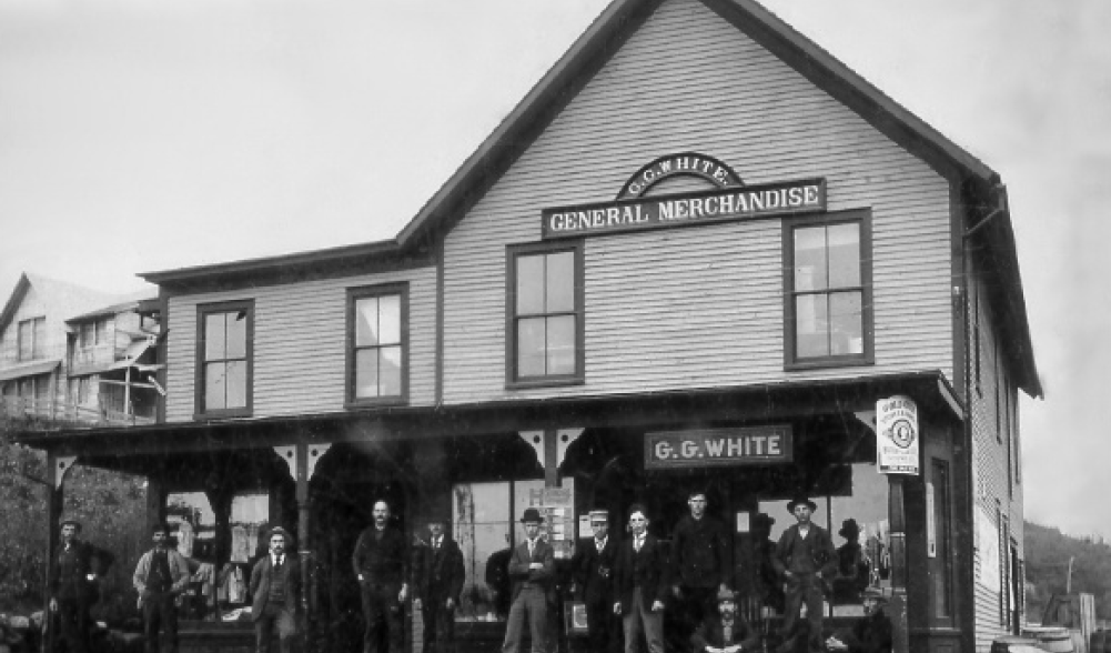 An antique black and white photograph of the general store in Newman, with men standing on the porch.