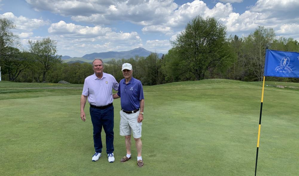 Craig Wood golf pro Jeff Estes and staff member Dick Strack pose on a green with Adirondacks in the background.