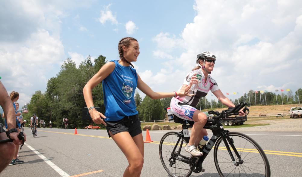 A volunteer hands off a bottle of water to a cyclist during the Ironman triathlon