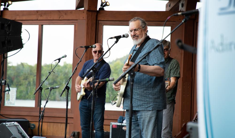 Three men perform music on a stage