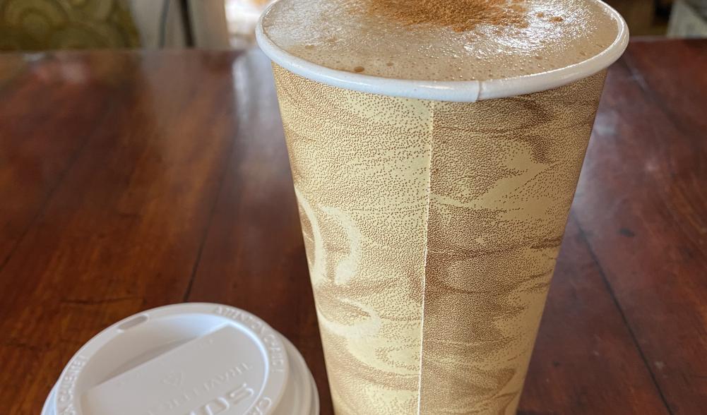 A foamy coffee drink on a wooden counter.