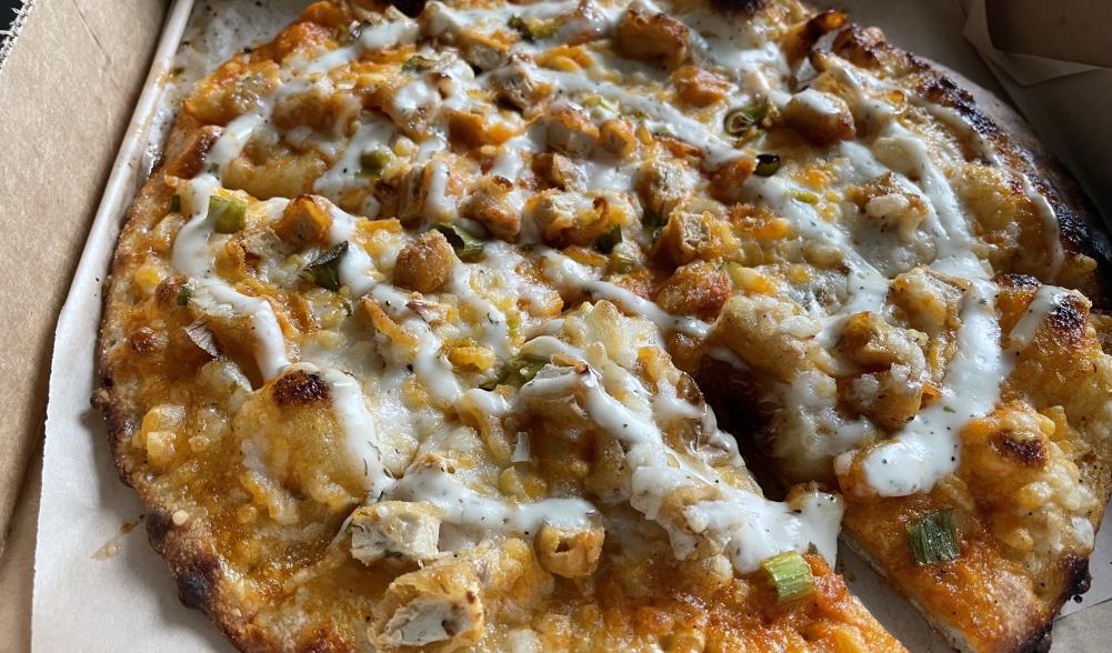 Vegan Buffalo "chicken" pizza baked with a drizzle of vegan "blue cheese" on top.