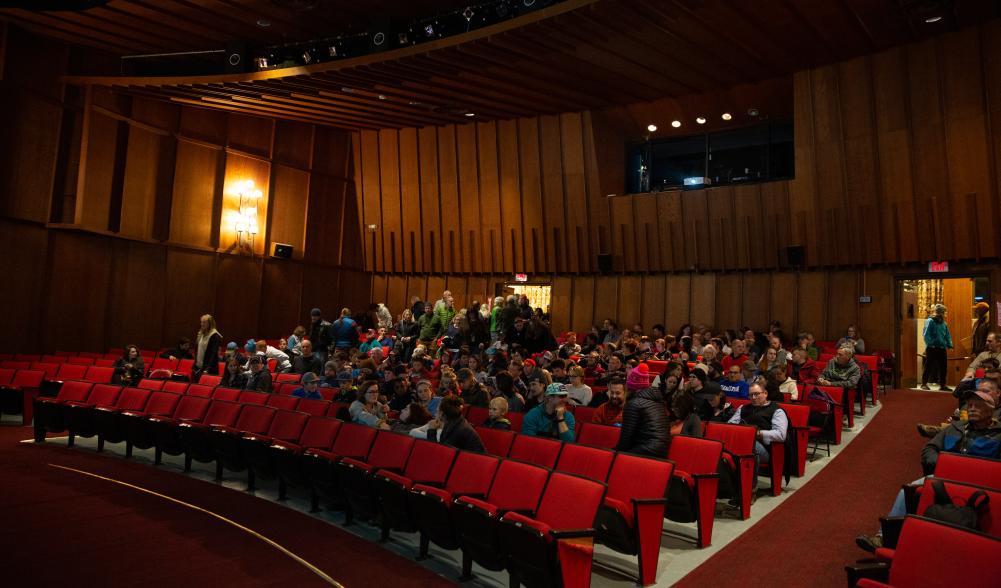 A seated crowd in a movie theater waiting for the show to begin