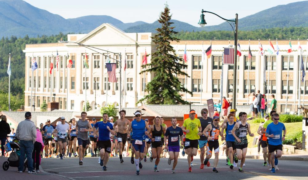 Runners race down a road as spectators look on.