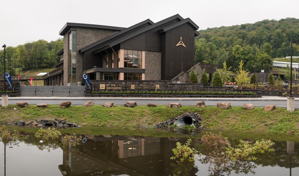 The new, modern Mountain Pass Lodge is classic Adirondack rustic design with a modern twist. It is surrounded by trees and hills.