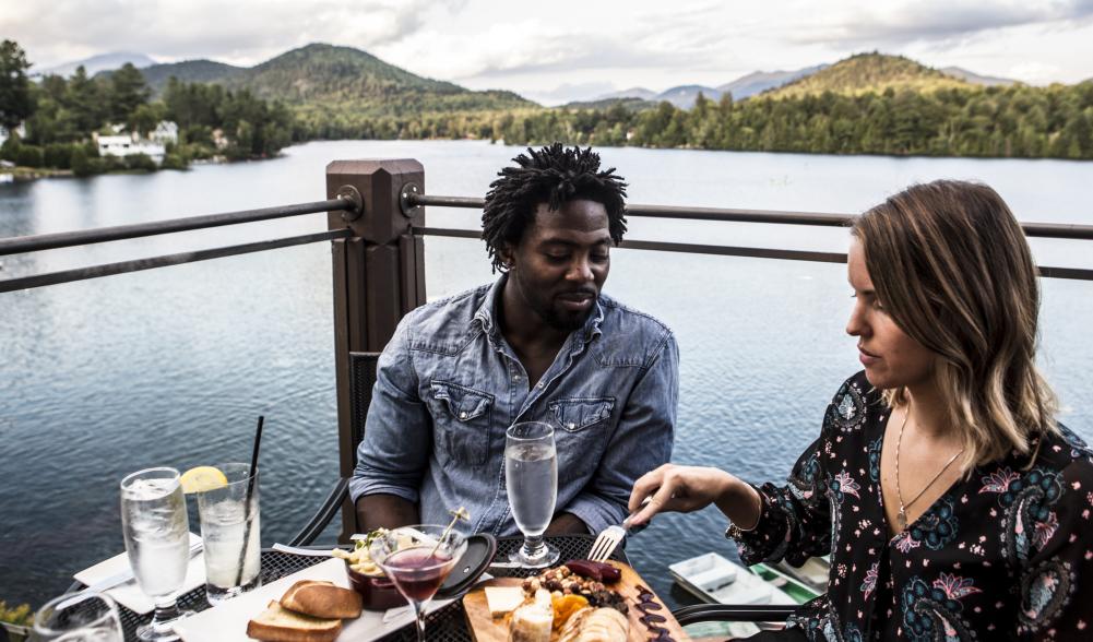 Two people sit with their drinks by the lake