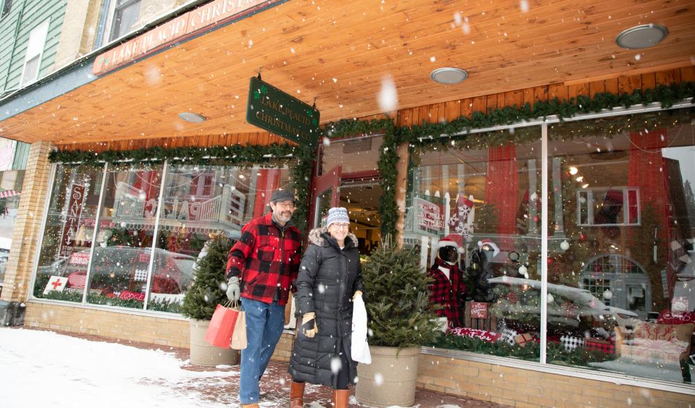 A couples walks out of the Christmas store carrying a shopping bag.