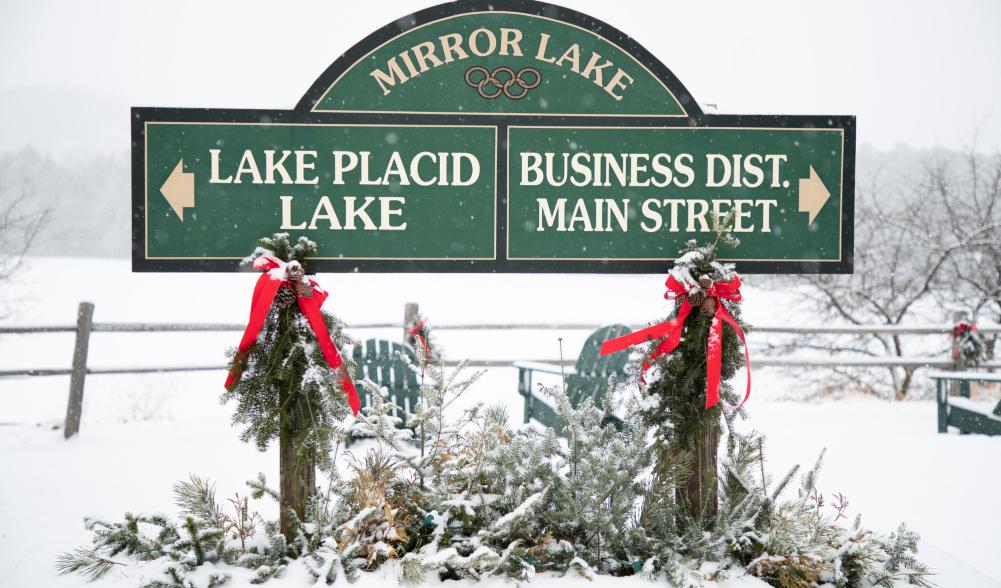 A snowy backdrop for the green Lake Placid Main Street sign.