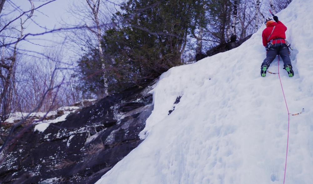 Man swinging ice axe on a wall of ice