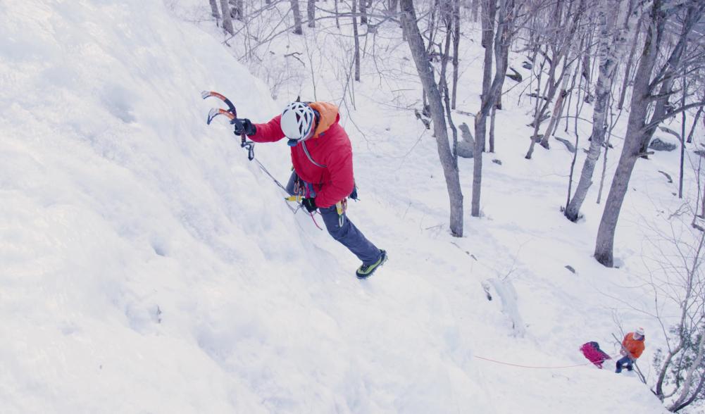 Man ice climbing with his belayer far below