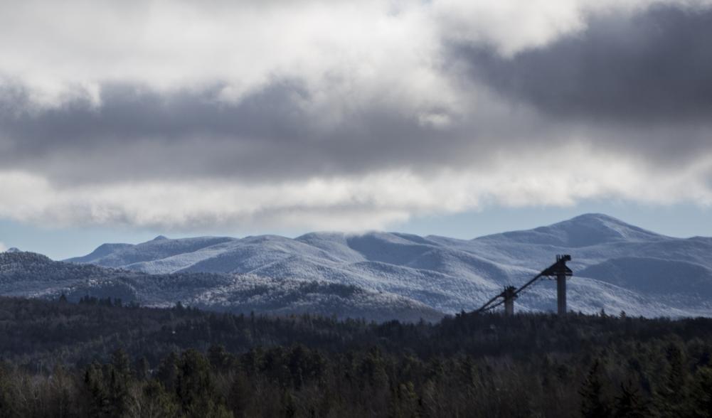 A view of the ski jumps in Lake Placid with snowy mountains behind them.