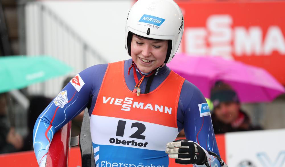 Ashley holds her sled and smiles after finishing her run.