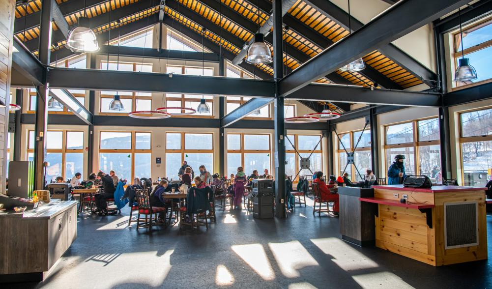 A large, open and airy dining room in the new lodge with lots of windows and happy diners.