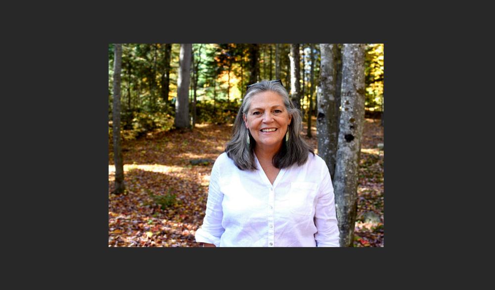 A woman smiling at the camera in the forest.