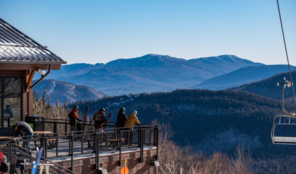 Group of friends hangs out on the porch of the midstation lodge with the mountains in the background