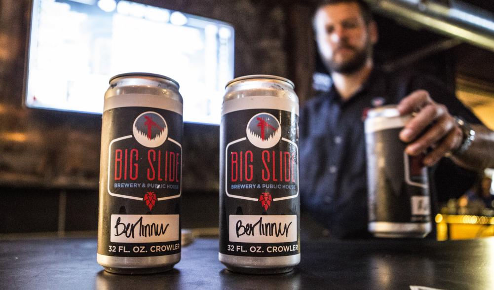 A bartender serves crowlers of beer for patrons to take home.