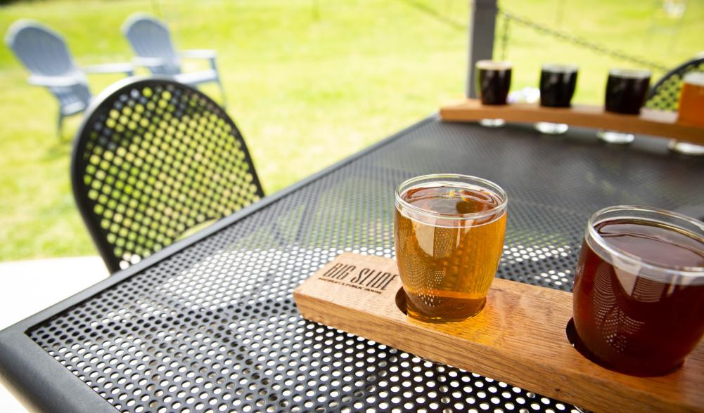 Flights of beers sit on tables outside.